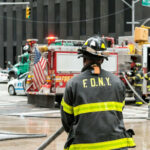 Firefighter in FDNY uniform overseeing emergency response at a city intersection