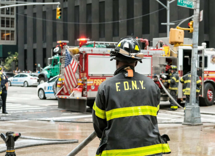 Firefighter in FDNY uniform overseeing emergency response at a city intersection