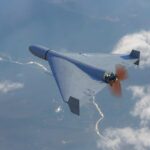 A drone flying high above the clouds with a visible propeller