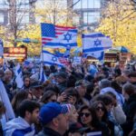 Crowd waving Israeli and American flags at a city rally