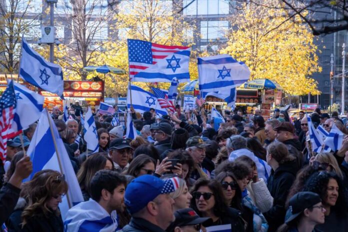 Crowd waving Israeli and American flags at a city rally