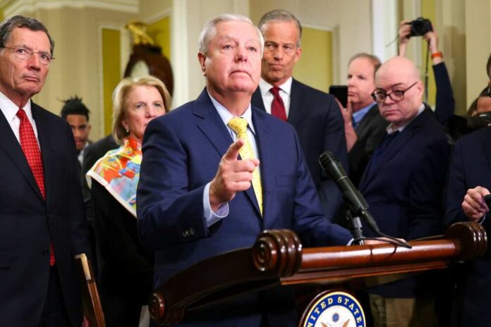 A group of government officials at a press conference with one speaking into a microphone