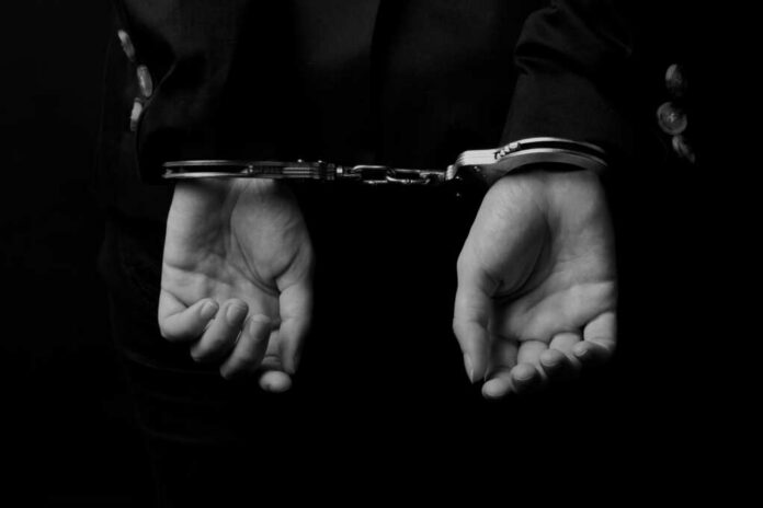 Hands in handcuffs against a dark background