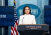 Woman in white suit speaking at White House press podium
