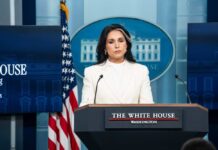 Cancer Battle or Political Crossfire? Gabbard’s Exit Woman in white suit speaking at White House press podium