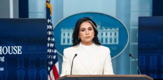 Woman in white suit speaking at White House press podium