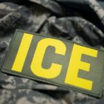 Close-up of a military patch with the letters ICE on a camouflage background