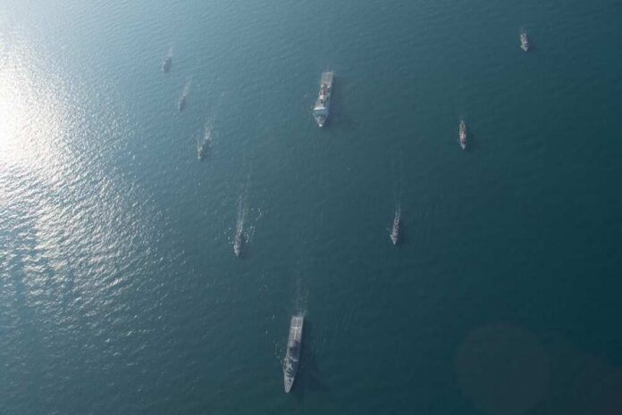 Aerial view of multiple naval ships navigating in the ocean