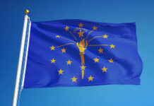 Indiana state flag waving against a blue sky