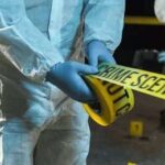 Forensic investigators in protective suits setting up crime scene tape