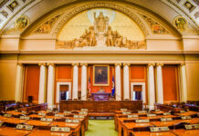 Interior view of a legislative chamber with wooden furniture and decorative ceiling