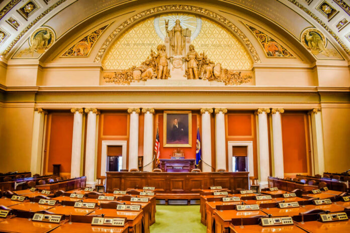 Interior view of a legislative chamber with wooden furniture and decorative ceiling