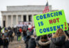Shocking Accusation, Evidence Missing A crowd at a protest with a sign reading COERCION IS NOT CONSENT! in front of the Lincoln Memorial