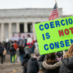 A crowd at a protest with a sign reading COERCION IS NOT CONSENT! in front of the Lincoln Memorial