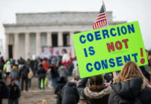 A crowd at a protest with a sign reading COERCION IS NOT CONSENT! in front of the Lincoln Memorial