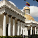 Exterior view of a government building with a golden dome and Venezuelan flag