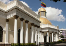 Exterior view of a government building with a golden dome and Venezuelan flag