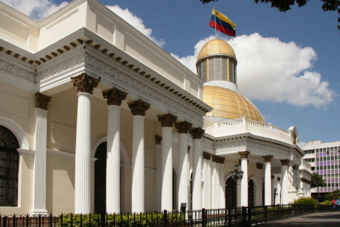 Exterior view of a government building with a golden dome and Venezuelan flag