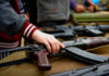 Hand touching assault rifle on display table