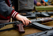 Hand touching assault rifle on display table