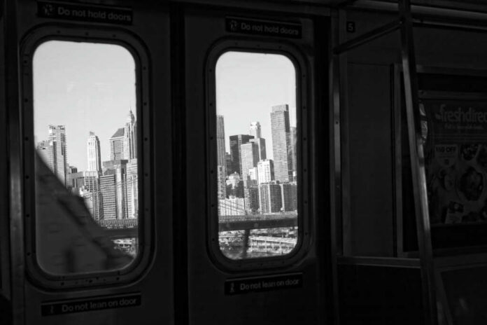 View of a city skyline through subway windows in black and white