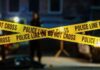 Shots Erupt Near Parade: Suspects Vanish Police tape marking a crime scene with blurred figures in the background