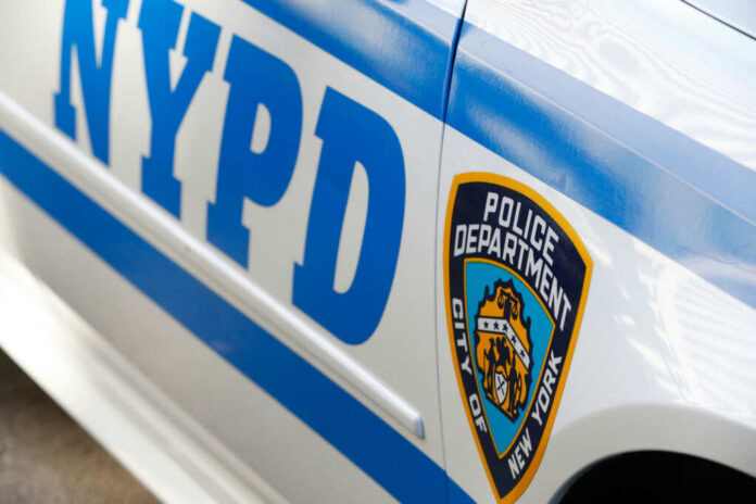shutterstock_2493498483 Close-up of a New York Police Department vehicle showcasing the badge and blue stripes