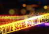 Texas Standoff Exposes ‘Secure’ Spin Yellow police tape marking a crime scene with blurred lights in the background