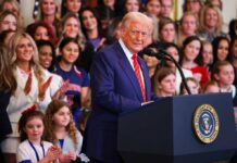 A speaker at a podium addressing a diverse audience during a political event