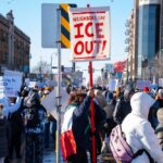 Crowd of protesters holding signs at a rally against ICE