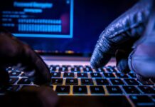 Dating Apps Expose Hidden Bases Close-up of gloved hands typing on a laptop keyboard in a dark setting