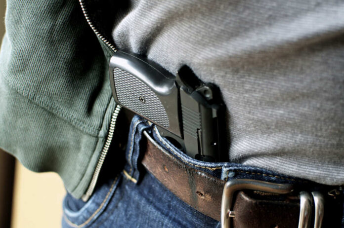 shutterstock_90457432 A handgun partially visible in a belt holster worn by a person in casual clothing