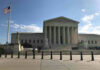 Supreme Court building with flag and people outside.