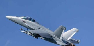 Twin-engine fighter jet climbing in a clear blue sky