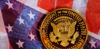 A commemorative coin featuring the presidential seal and the name Donald Trump on an American flag background