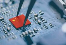 Microchip with China flag held by tweezers on circuit board