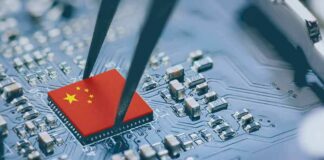 Microchip with China flag held by tweezers on circuit board