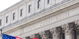 Facade of a United States courthouse with an American flag in the foreground