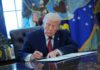 Trump’s Monument Speedway Sparks Fury A person in a suit signing documents at a desk in the Oval Office