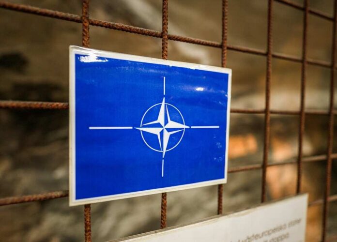 Gothenburg,,Sweden,-,January,25,2026:,Nato,Emblem,Sign,Mounted NATO emblem on a blue sign attached to a rusty wire fence