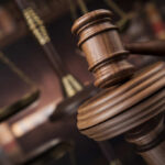 Close-up of a wooden gavel with scales of justice in the background