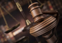 Close-up of a wooden gavel with scales of justice in the background