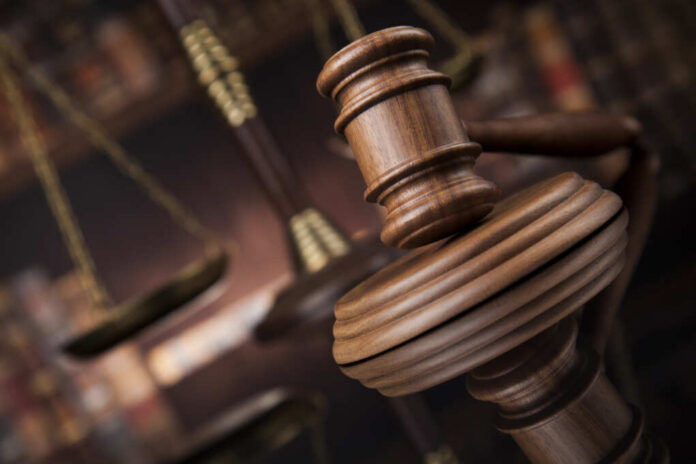 Close-up of a wooden gavel with scales of justice in the background