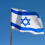 Israeli flag waving against a clear blue sky