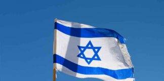 Israeli flag waving against a clear blue sky