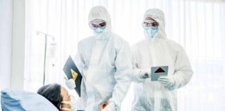Healthcare workers in full PPE attending to a hospital patient