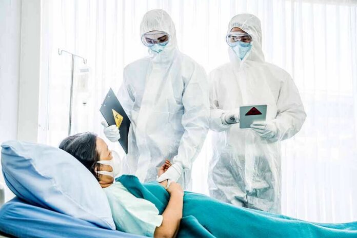 Healthcare workers in full PPE attending to a hospital patient
