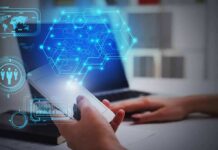 Hands using smartphone near laptop with digital hexagon interface overlay