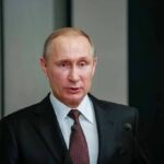man in suit speaking at a podium