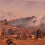 Wildfire burns on hillside near suburban homes